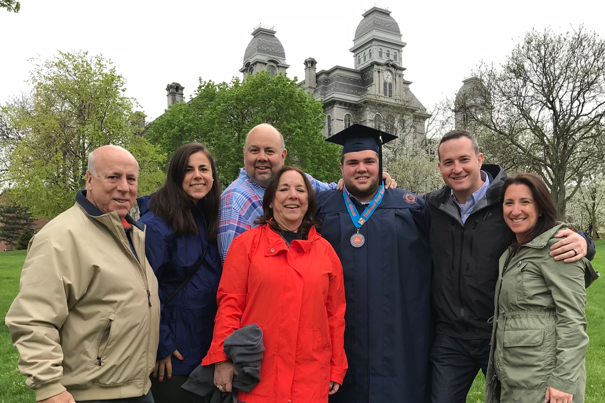 Members of a family pose for a graduation photo in front of the Hall of Languages.