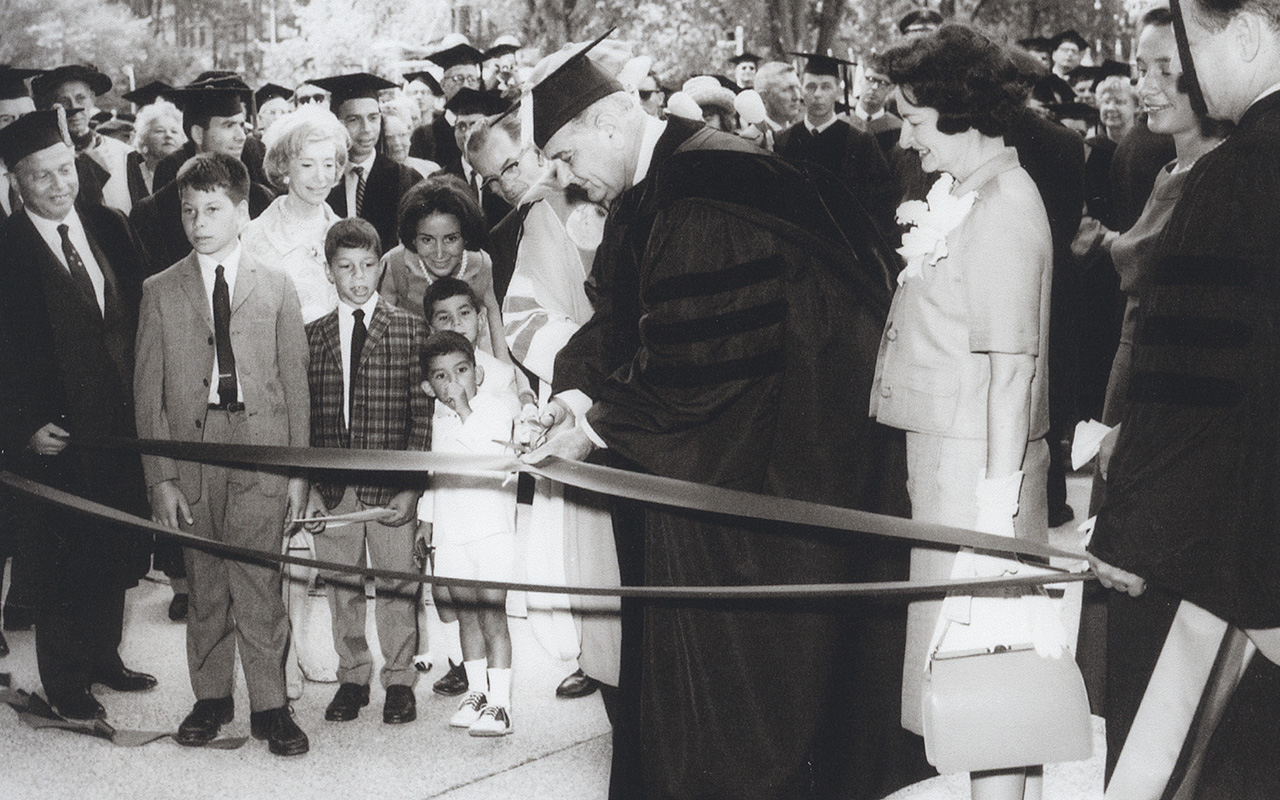 person cutting ribbon in front of a line of people standing outside