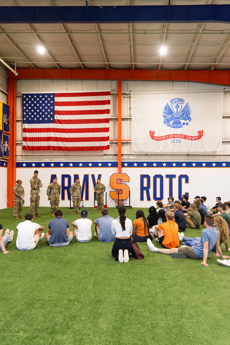 ARMY ROTC facility with students sitting on the grass field while facing people in military uniforms