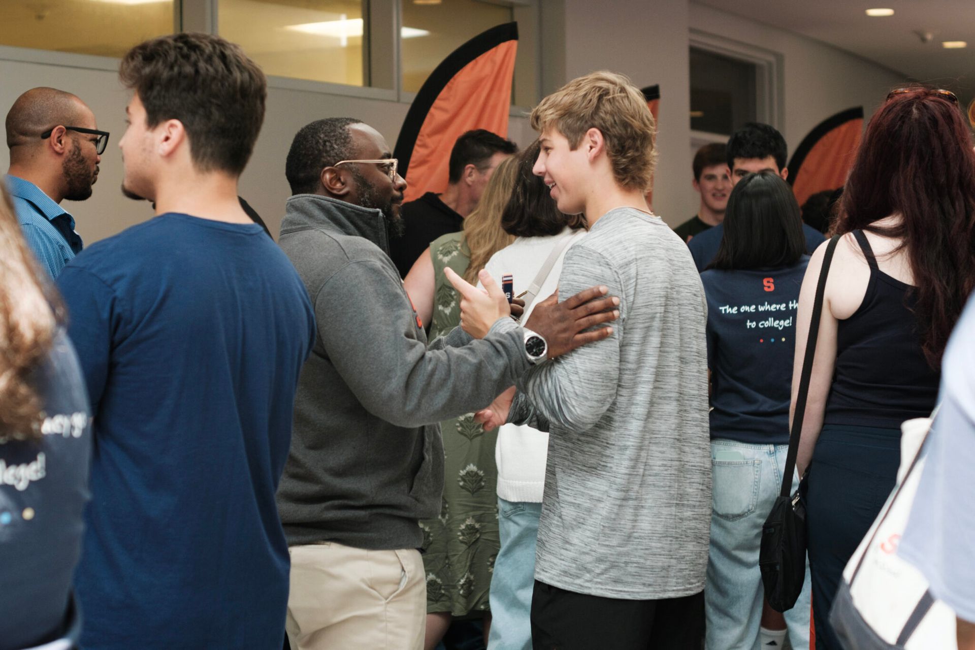 Two people are standing and talking to other people in a room.