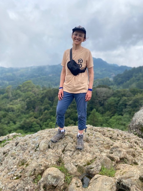 Person standing on top of a rocky hill. 