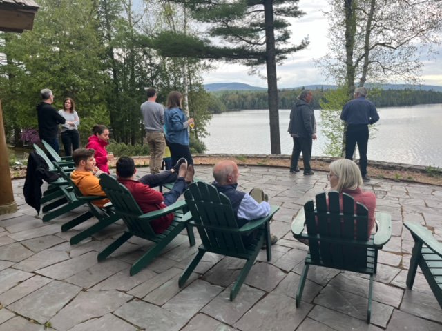 group of people sitting and standing in front of lake