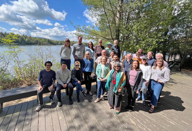 group of people standing outside in front of lake