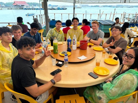 group of students seated around a table near waterfront