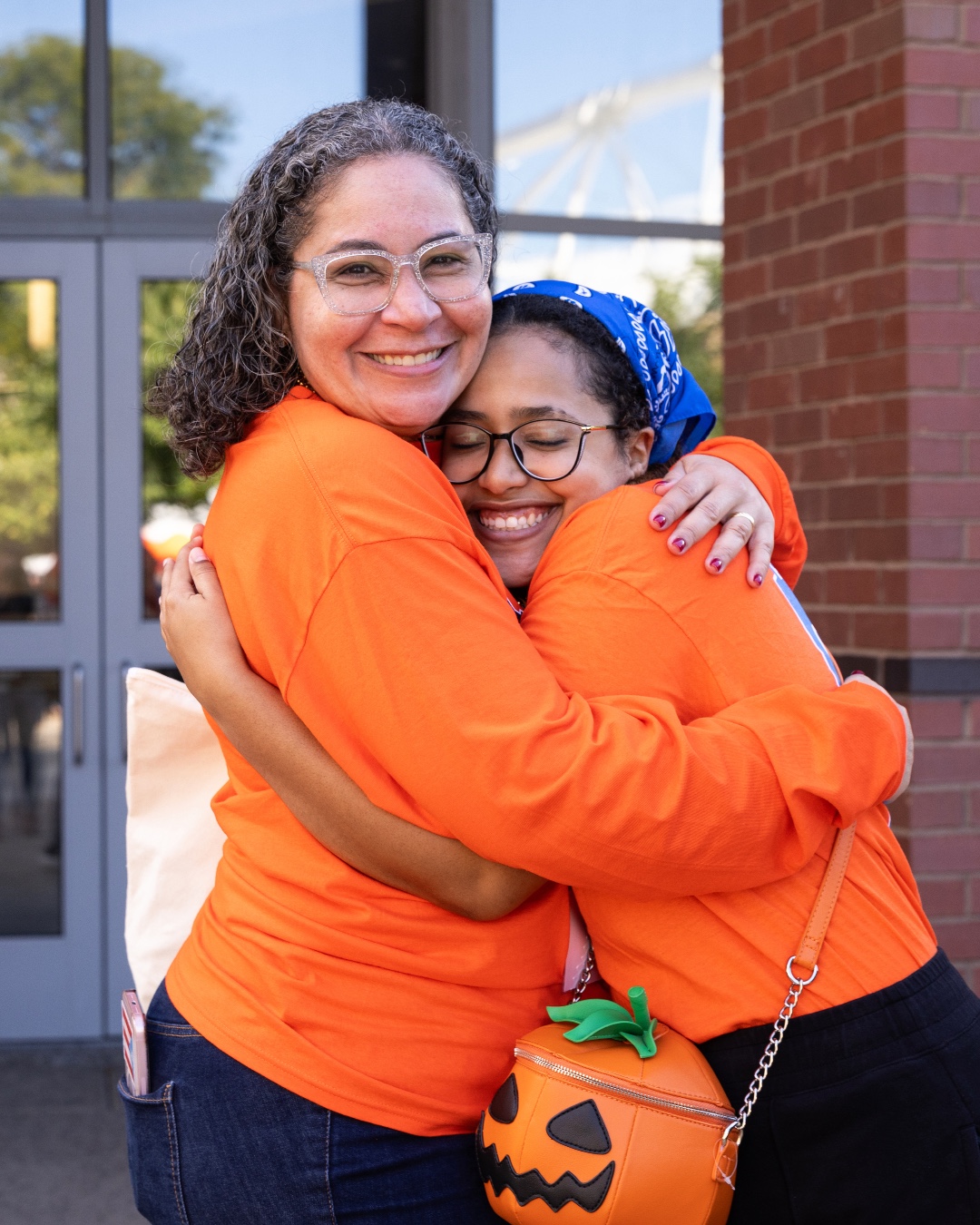 Two people embracing in front of a building entrance.