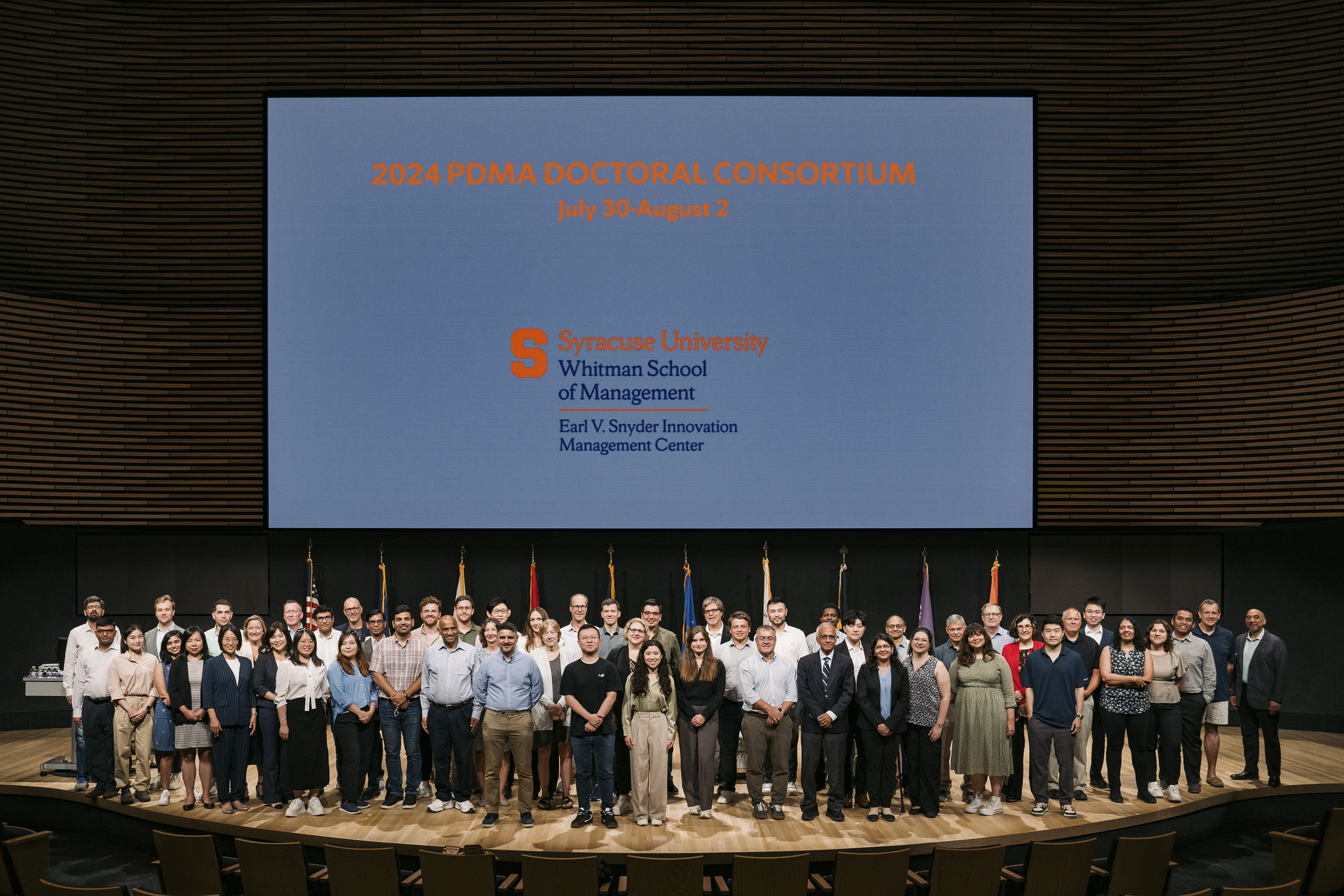 group of people standing in front of large screen on stage