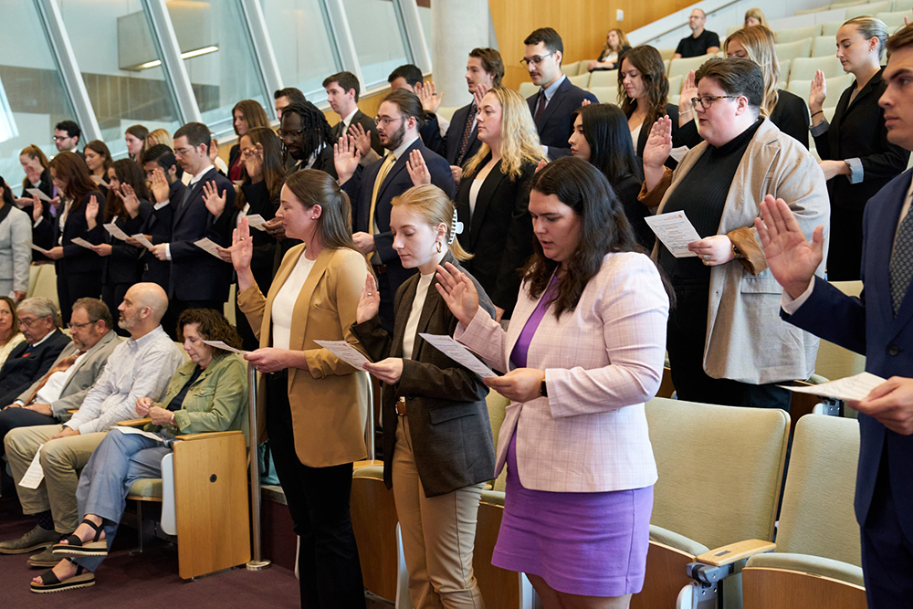 student attorneys stand up in a court room for a swearing-in ceremony