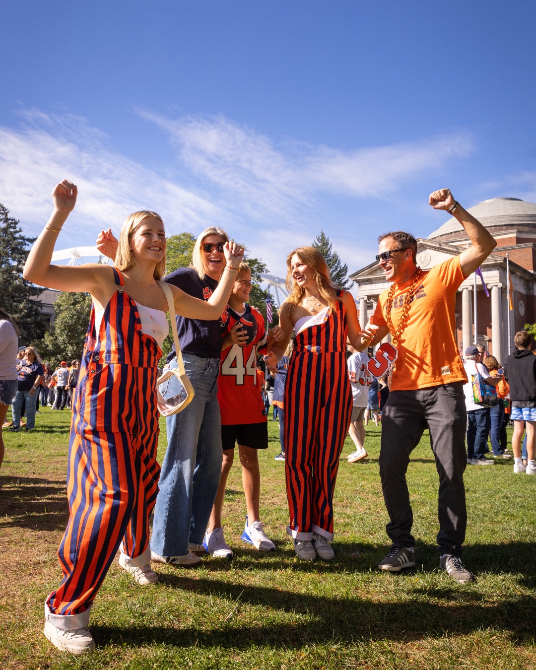 Group of people in sportive attire cheering outdoors.