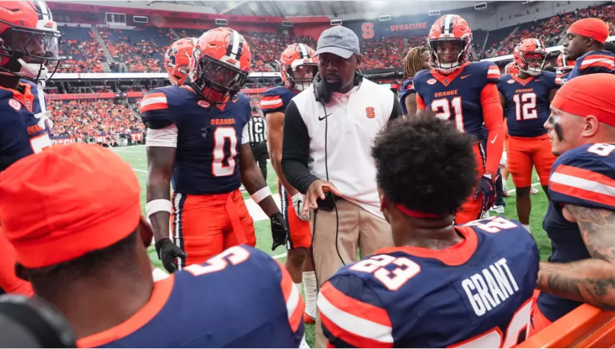 A head football coach talks to his players during a game.