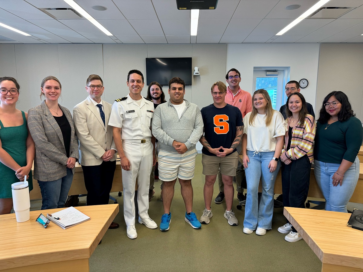 person in uniform standing with a group of students