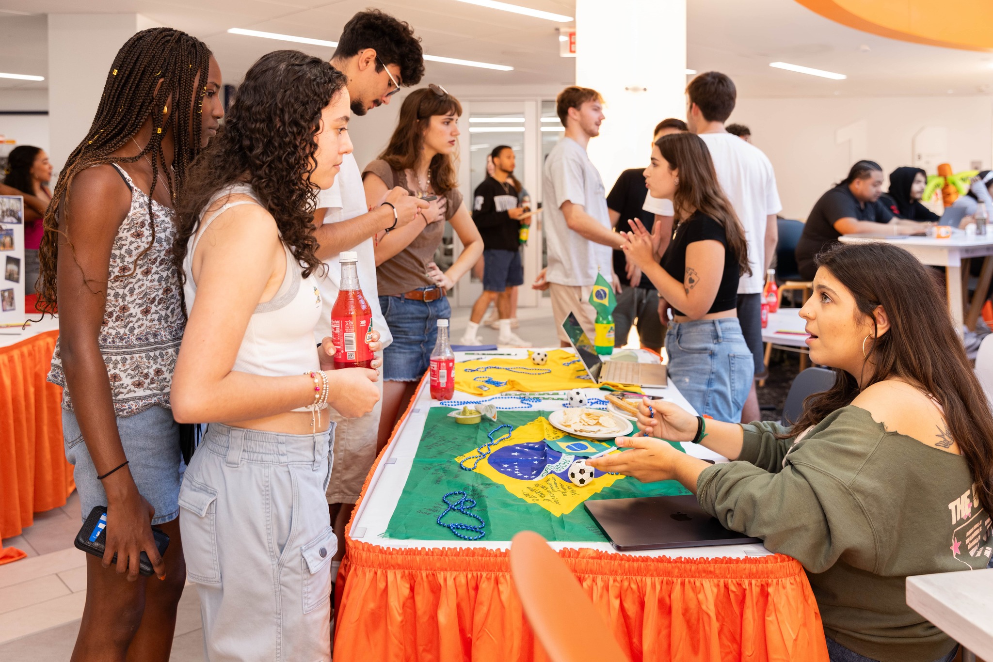 people standing in front of table speaking with people seated at table in Schine Student Center