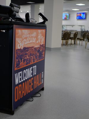 a sign on a dining center check-in kiosk says "Greetings from Syracuse, NY, Welcome to Orange Hall, est. 2024"