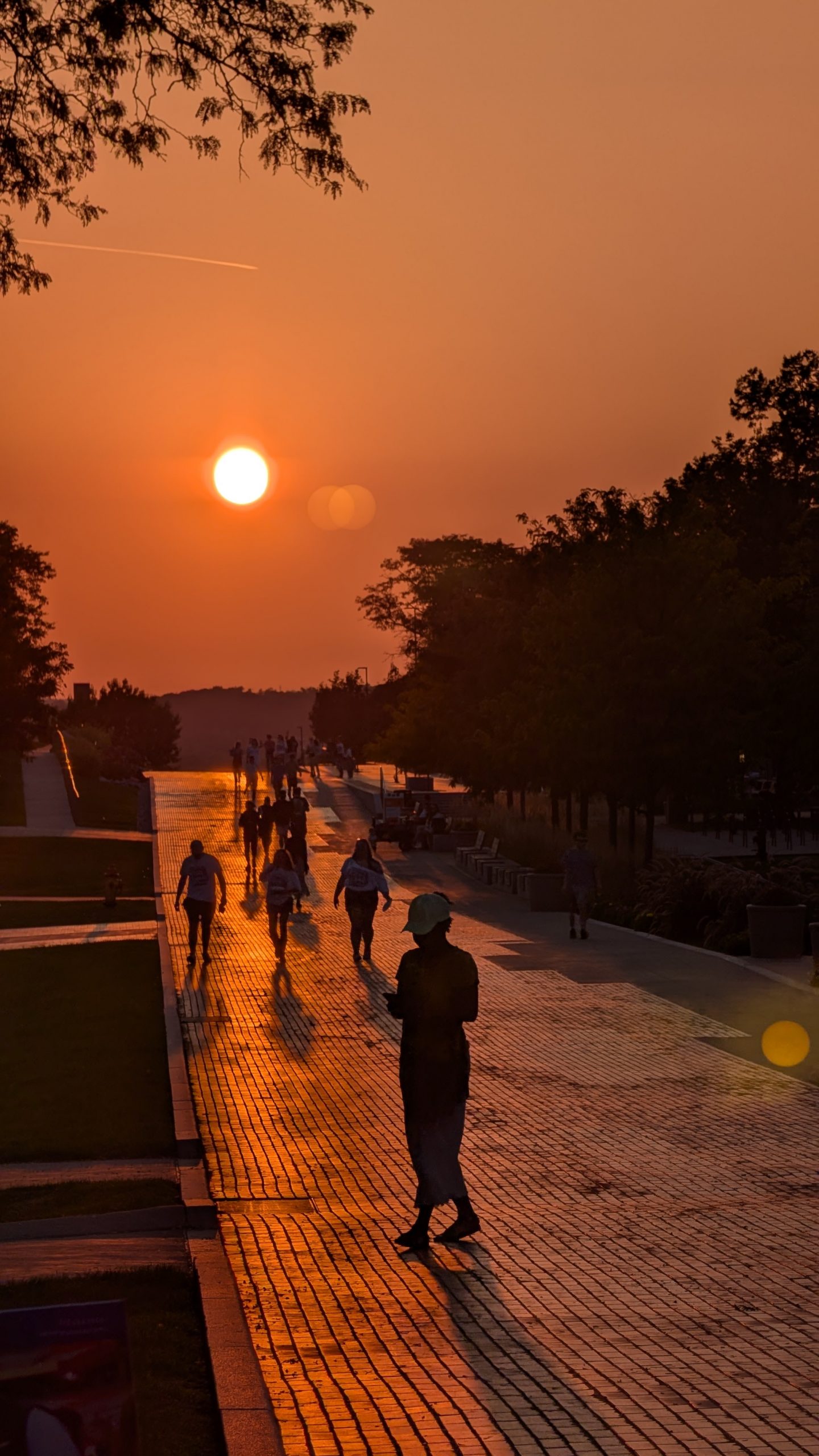 Sunset on the Promenade with people walking along the path under an orange sky.