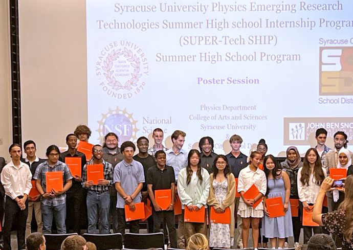 Students pose for a photo in front of their poster presentations.