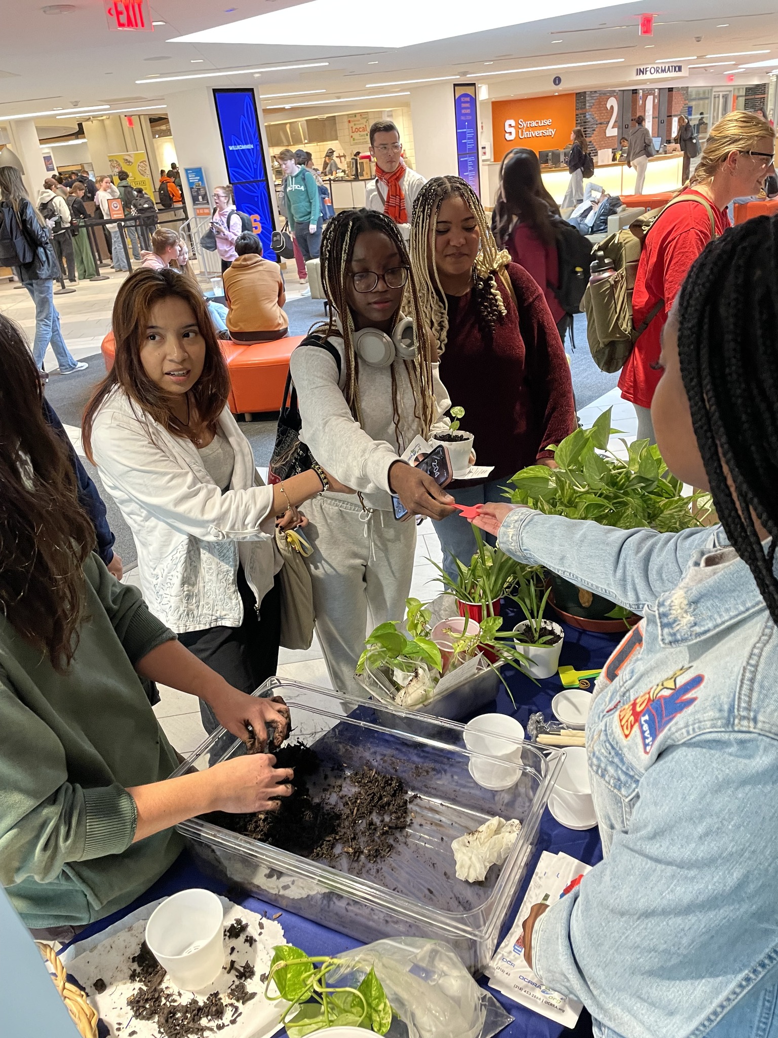 Individuals participating in a planting activity at a busy indoor event.