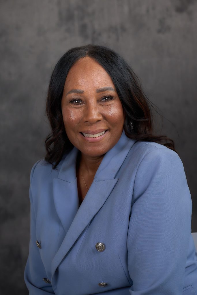 Portrait of Diane Crawford wearing a light blue blazer, smiling against a gray background.