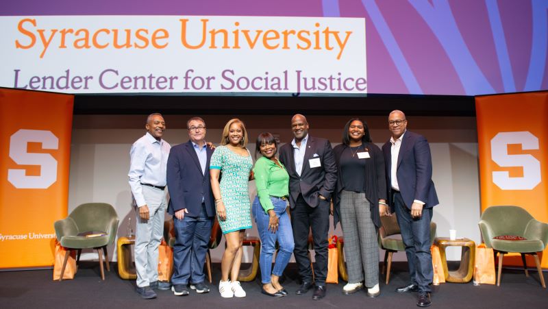 seven people gather on stage and pose in a line for a group photo