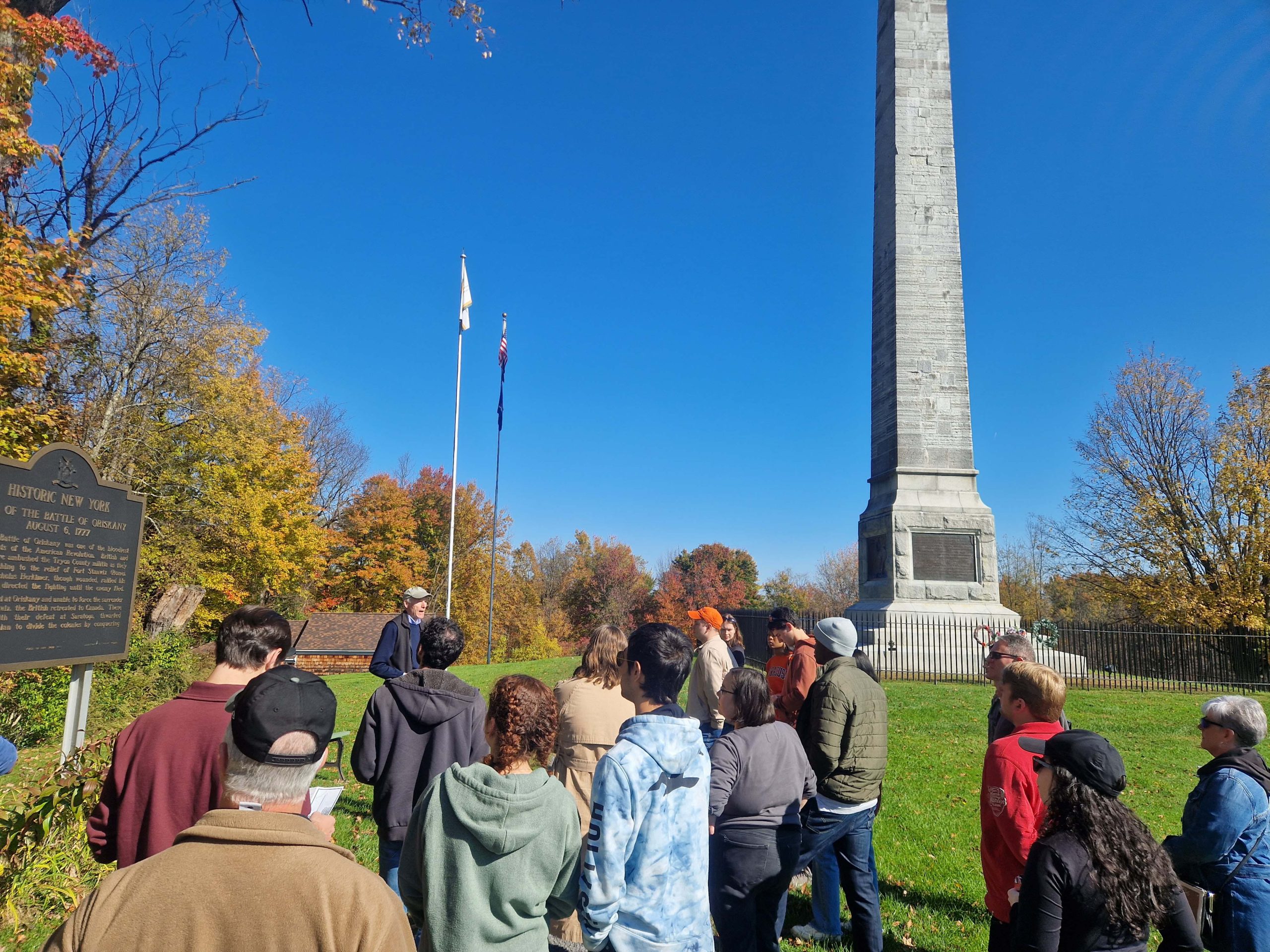 Group of people attending a guided tour in Oriskany on a sunny day with clear blue skies.