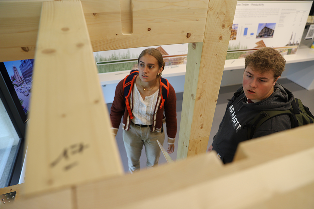 Two students are examining a digital display at a Timber Framing exhibition