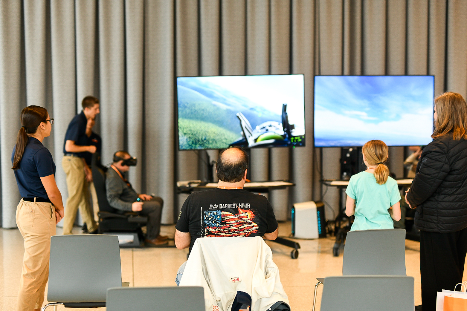 Four people viewing and interacting with flight simulation screens in a modern indoor setup.