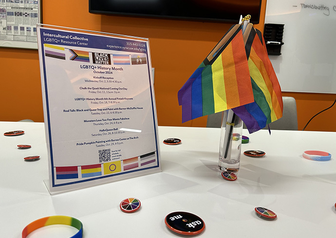 table top with a sign with events listed and a container with rainbow flags