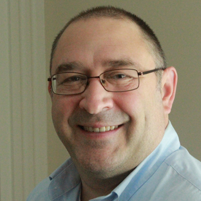 A man smiles while posing for a headshot.