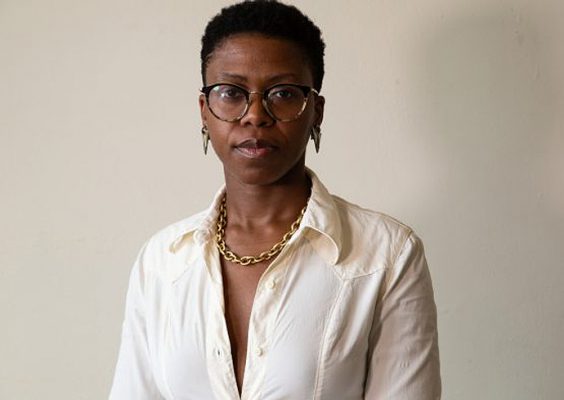 A person poses for a headshot in front of a white backdrop.