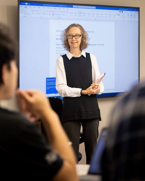 woman standing teaching with students in audience