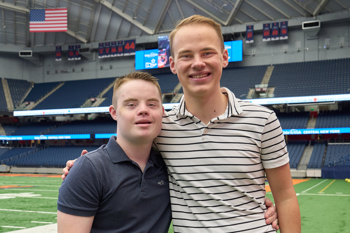 Two brothers embrace while posing for a headshot inside the JMA Wireless Dome.