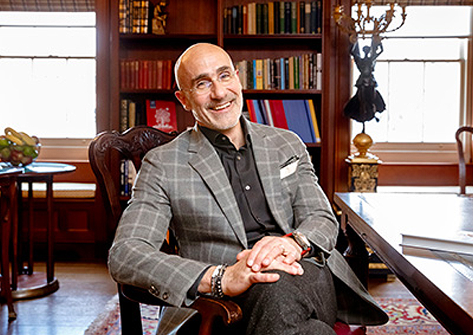 A man smiles while posing for a headshot inside a library with books in the background.