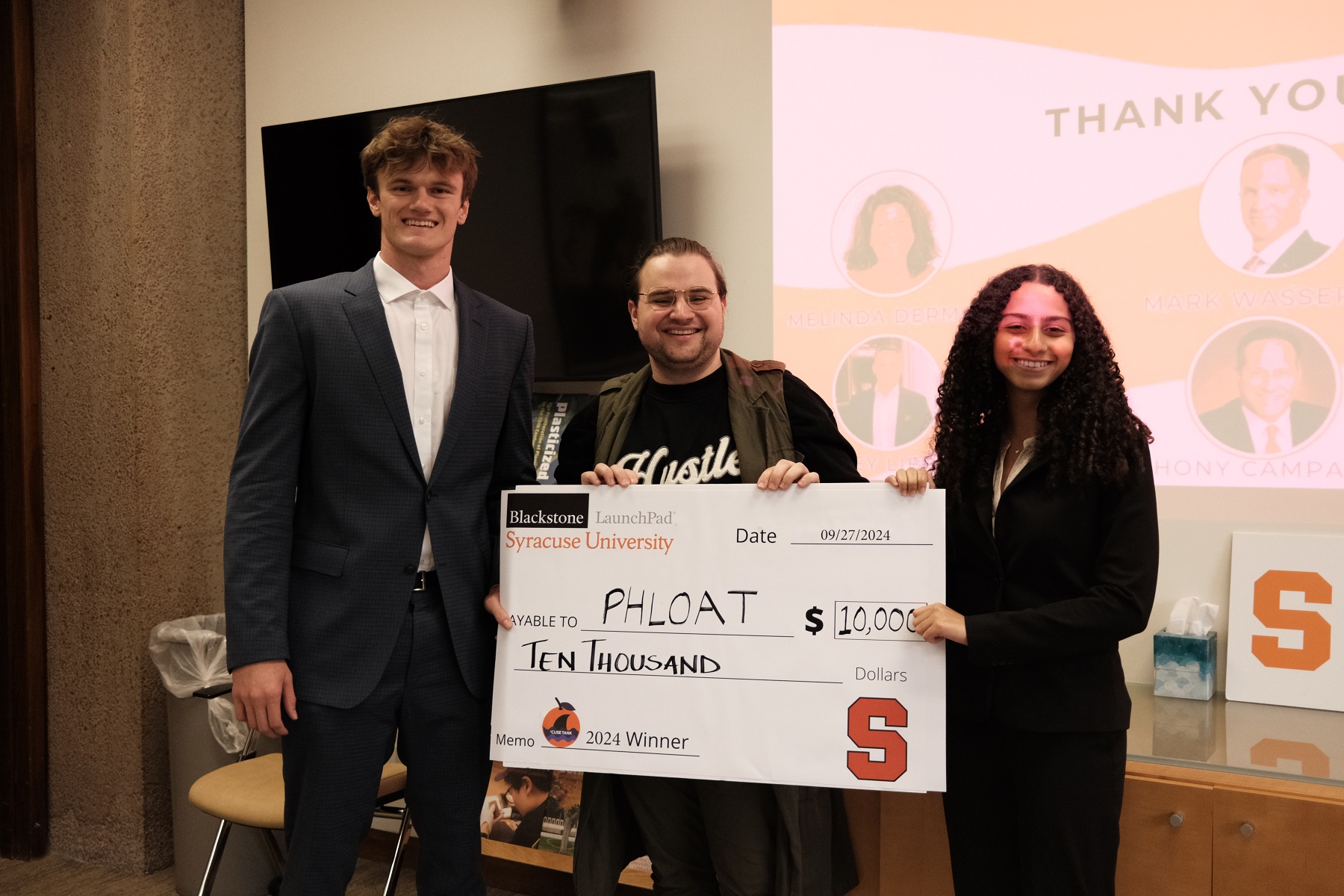 Three people holding an oversized check for $10,000