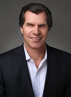 A man smiles while posing for a headshot.