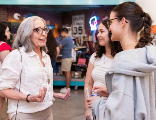 woman speaks to two students at an event