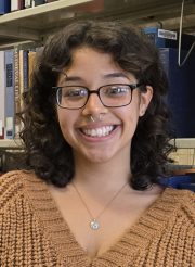 young woman with glasses and shoulder length dark hair smiling