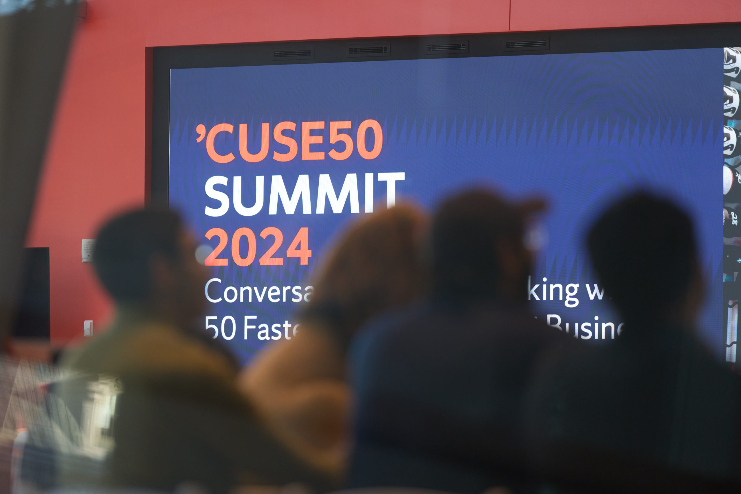 Audience members viewing a presentation at the 'CUSE50 Summit 2024, featuring discussions on harnessing the potential of 50 fast-growing businesses.