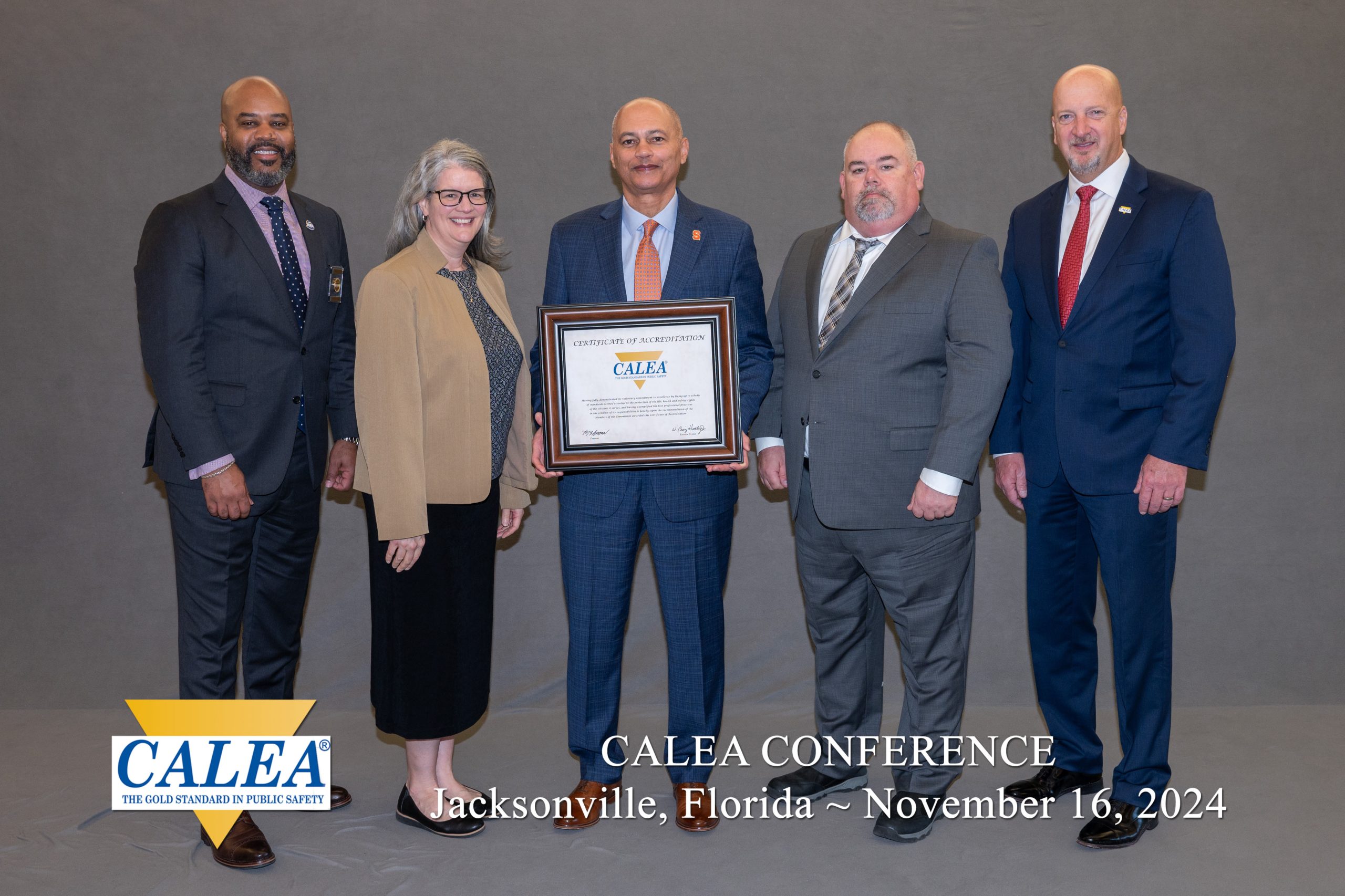 Group of five individuals standing with a CALEA accreditation certificate at the CALEA Conference in Jacksonville, Florida, dated November 16, 2024.