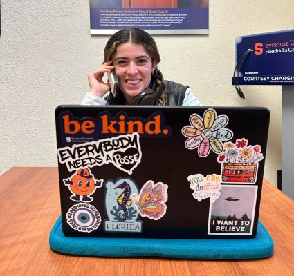 Person sitting at a desk with a laptop covered in stickers.