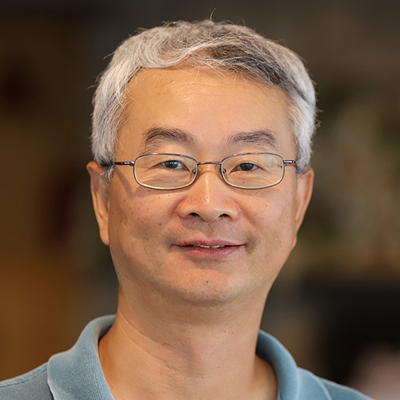 A man poses for a headshot while wearing glasses and a polo.