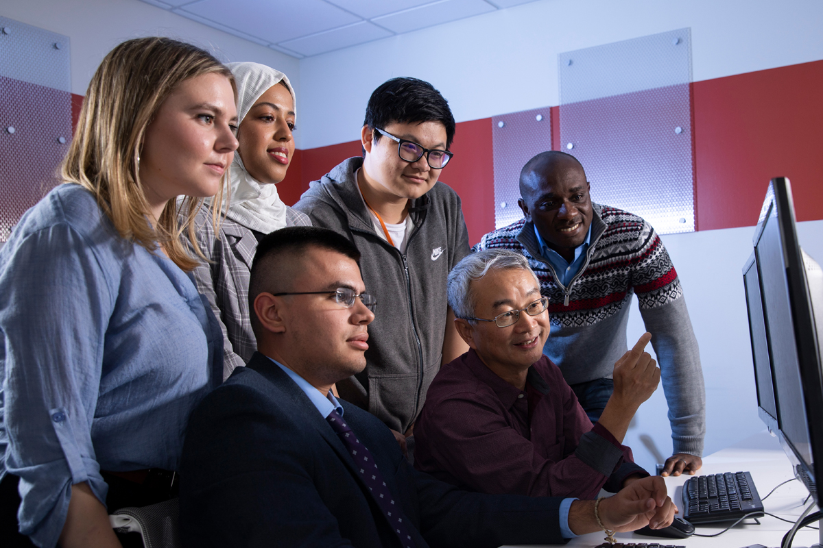 A professor discusses cybersecurity attacks with his students in a lab.