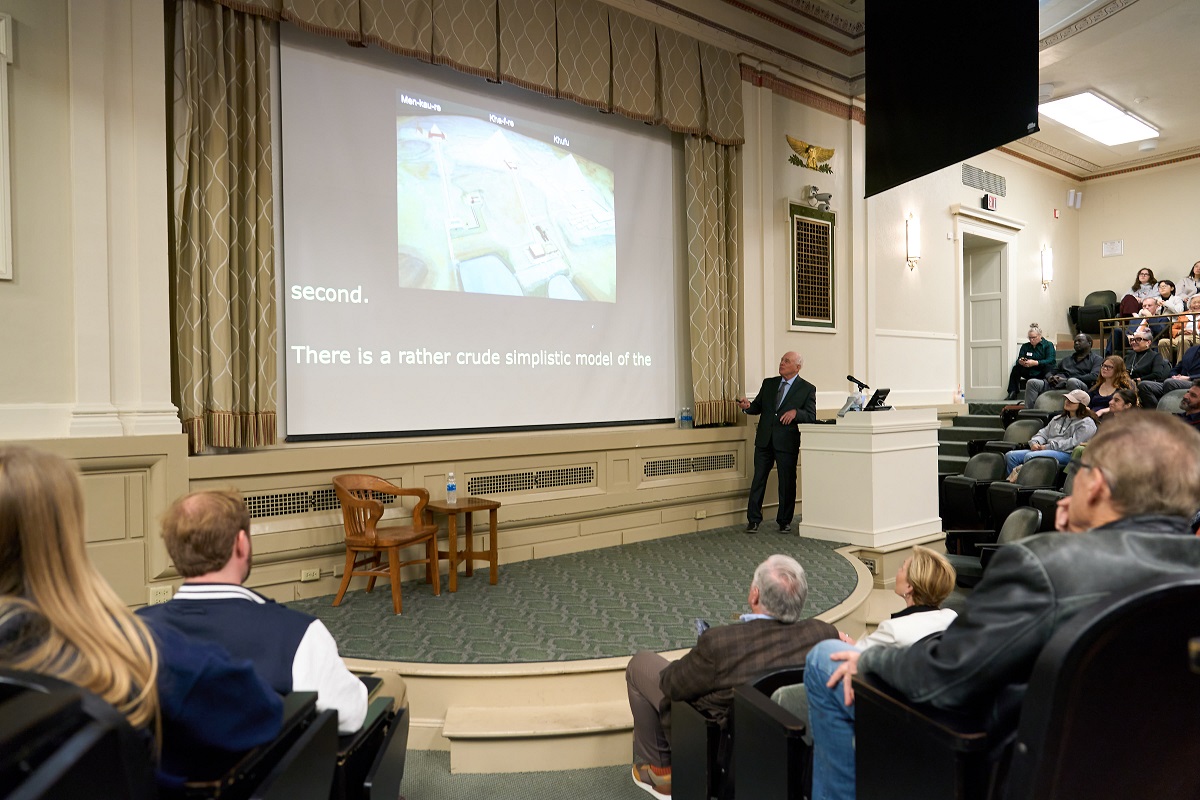 person speaking at a podium in Maxwell Auditorium in front of large crowd 