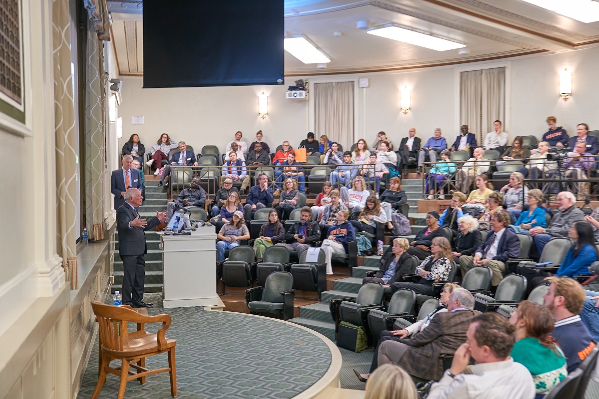 person speaking at a podium in Maxwell Auditorium in front of large crowd