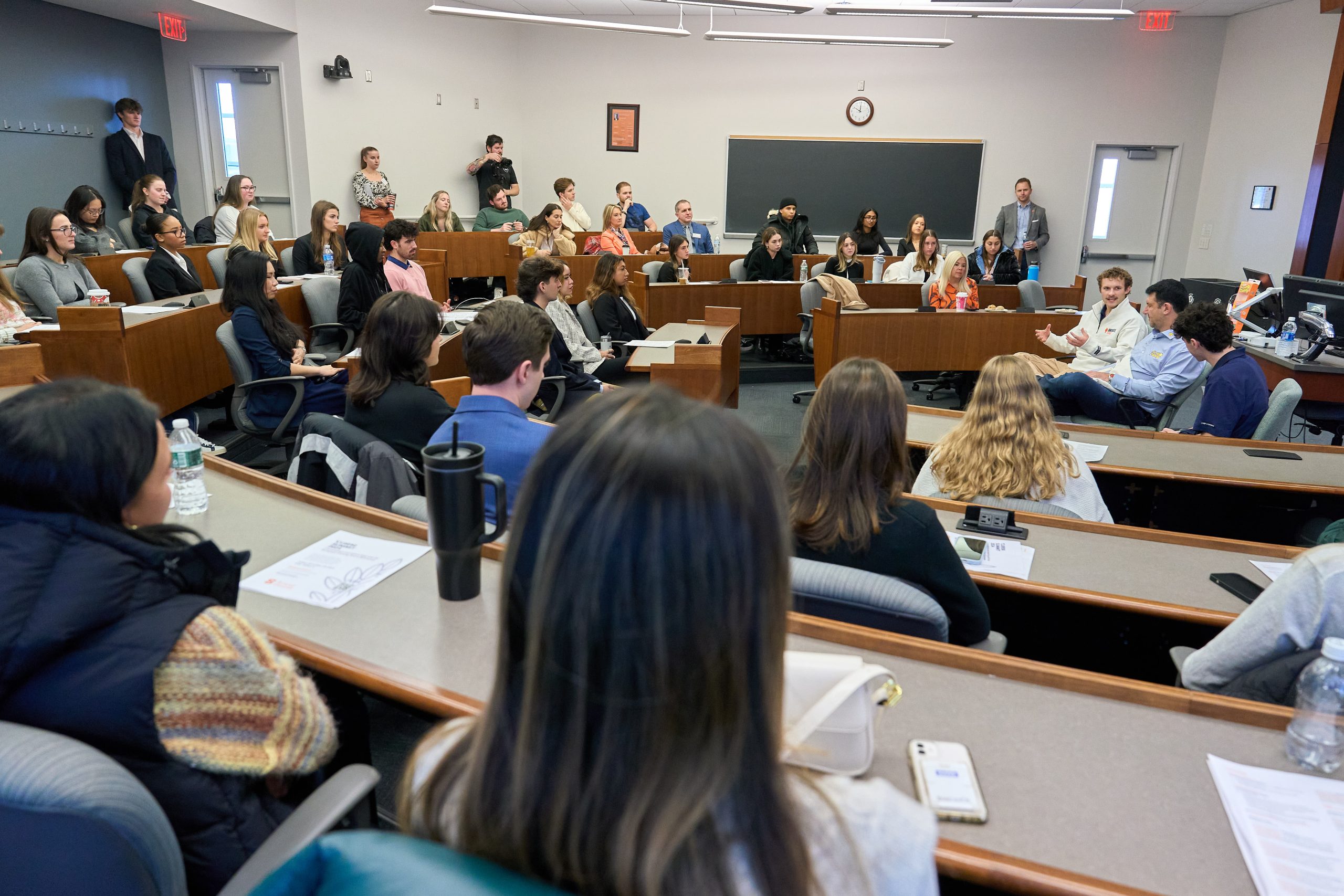 Students seated in a university classroom, engaged in a discussion with a speaker.