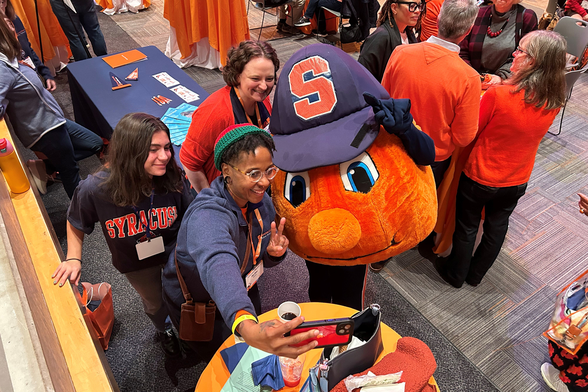 People smile while posing for a selfie with Otto during a breakfast.