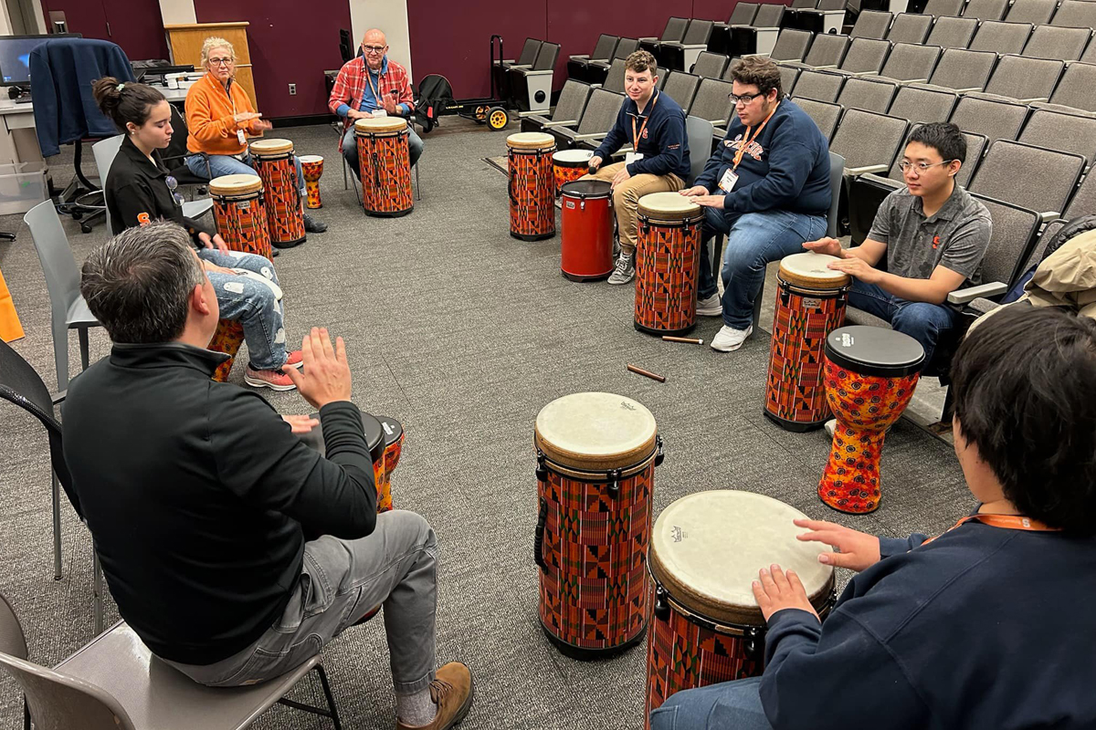 People seated in a circle playing the drums.