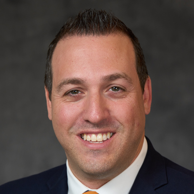 A man smiles while posing for a headshot.