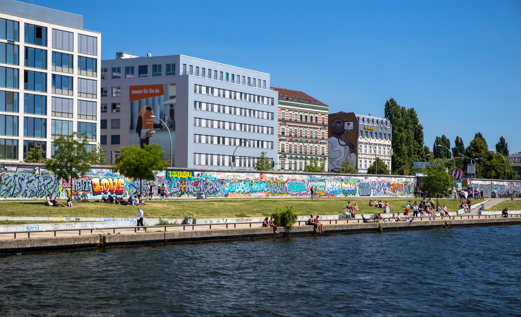 Berlin Wall bordering river with modern buildings in background