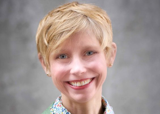 A professor smiles while posing for a headshot.