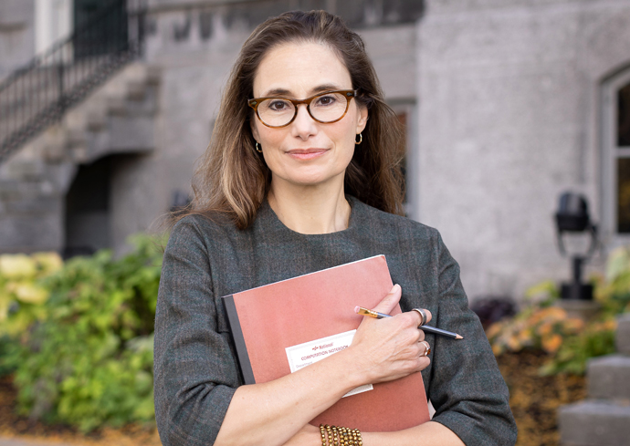 A woman smiles while posing with a book outside of the Hall of Languages.