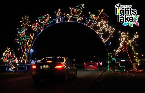 Vehicles driving through the Wegmans Lights on the Lake display, featuring illuminated archways and colorful light sculptures of festive characters and designs.