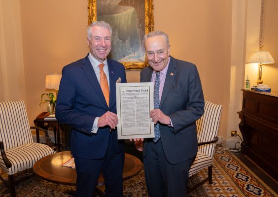 Sen. Charles Schumer, right, presents Maxwell Dean David M. Van Slyke with a copy of the remarks from the official congressional record commemorating Maxwell's centennial.